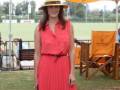 Mujer con vestido rojo y sombrero en un evento al aire libre.