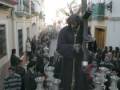 Imagen de una procesión religiosa en un pueblo, con una estatua de Jesús cargando la cruz y seguido por fieles en trajes tradicionales.