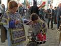 Fiesta religiosa en una calle adoquinada, con niños vestidos de trajes tradicionales y una procesión en el fondo.
