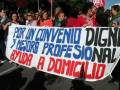 Una multitud de personas sostiene un cartel que pide un convenio digno y mejoras profesionales para el domicilio de ayuda.