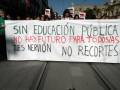 Manifestantes sostienen un cartel que dice "Sin educación pública no hay futuro para todas las niñas y niños, no recortes".