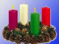 Adorno navideño con velas de colores rojo, blanco, verde y amarillo en un círculo de ramas de conífera y cono de pino.