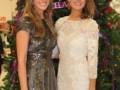 Dos mujeres posan frente a un árbol de Navidad decorado con luces y adornos. La imagen es parte de una celebración navideña, posiblemente en un evento o fiesta.
