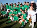 Equipo de fútbol celebrando, con una mujer en uniforme blanca y sombrero blanco.