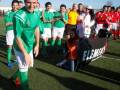 Fotografía de un equipo de fútbol celebrando en el campo, con una persona sonriendo y otros jugadores posando para la foto.