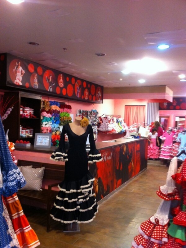Interior de una tienda con maniquíes vestidos, estantes con ropa y decoración navideña.