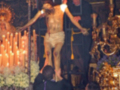 Imagen de una procesión religiosa con un hombre vestido como el Cristo Crucificado, rodeado por fieles y adornos dorados.