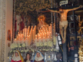 Imagen de una iglesia con un altar en el centro, adornado con velas y flores. En la parte superior, hay un crucificado y estatuas religiosas a ambos lados. La imagen muestra una escena de devoción y respeto hacia la religión.