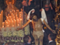 Imagen de una procesión religiosa con un Cristo crucificado y fieles rezando.