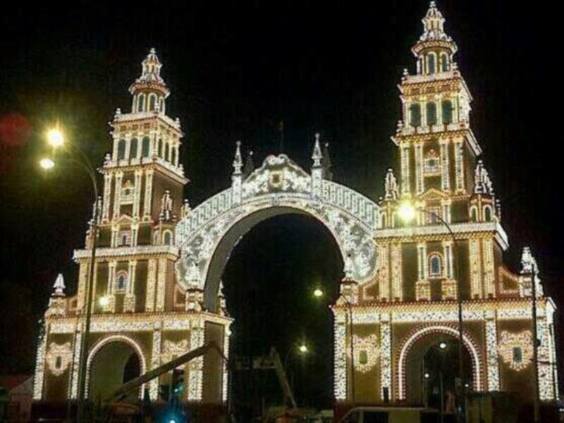 Puerta monumental iluminada en la noche, con dos torres altas y detalles arquitectónicos elaborados.