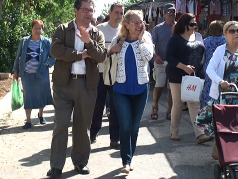 Una imagen de una calle con personas caminando, algunas con bolsas y otros con ropa.