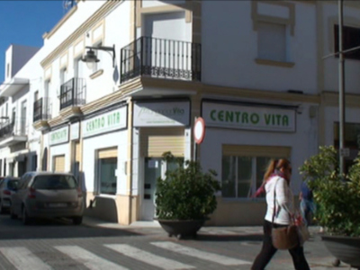 Calle con tienda 'Centro Vita' en una ciudad española, con peatonal y automóviles estacionados.