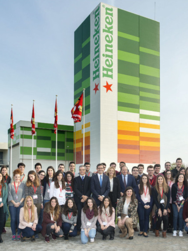 Grupo de personas posando frente a un edificio con la marca Heineken visible.