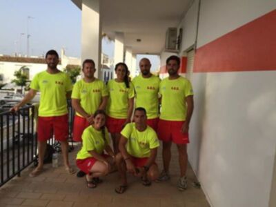 Un grupo de personas en ropa deportiva amarilla y roja posan frente a una pared con un balcón. Parecen estar en una zona urbana, posiblemente un área de entrenamiento o evento deportivo.