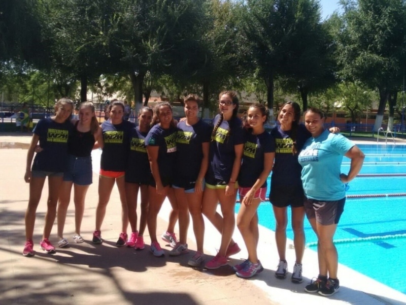 Estudiantes de la Escuela de Natación de la Universidad Autónoma de Nuevo León posan frente a una piscina. El equipo lleva camisetas con el nombre de la escuela y shorts cortos, listo para una competencia.