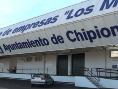La fachada de un edificio con el nombre "Librería de empresas 'Los Márkets' Ayuntamiento de Chipiona". La estructura tiene una cubierta blanca con letras azules y un carrito aparcado en el frente.