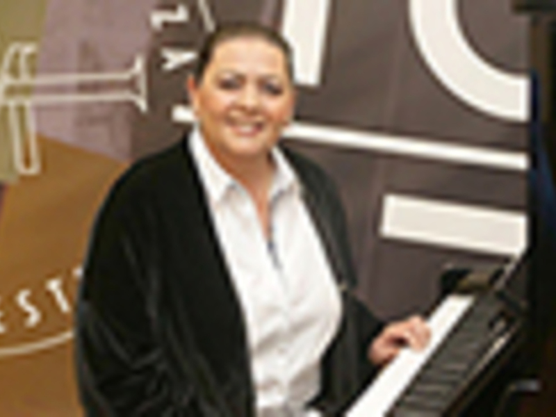Mujer sonriendo mientras toca el piano, fondo con logotipo de 'Estudio Musical'