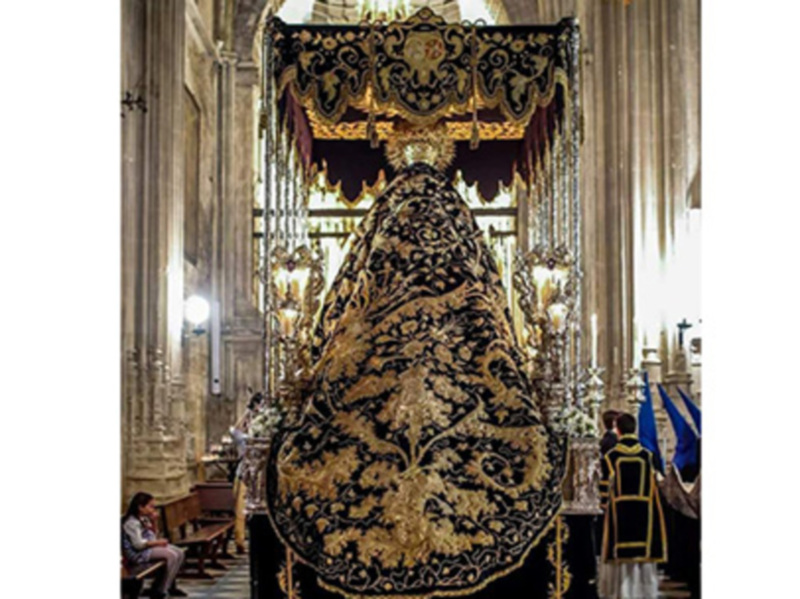 Procesión religiosa en la Catedral de Sevilla, con una imagen procesional de la Virgen María en un trono ornado.