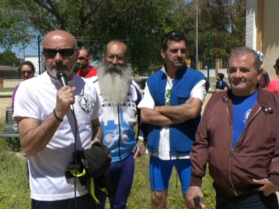 Un grupo de personas en una zona verde con flores amarillas, posiblemente participantes o asistentes a un evento deportivo.