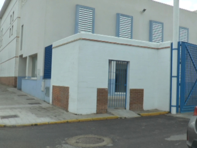 Edificio blanco con azulejos y puerta metálica, cerca de una calle con señales de tráfico.