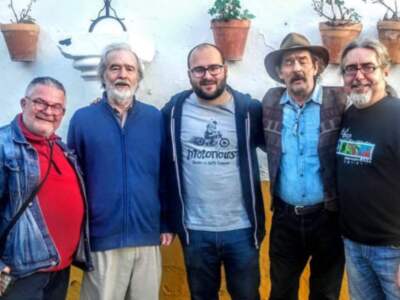 Grupo de amigos posando juntos en un entorno con macetas de plantas en la pared.