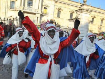 Un grupo de personas vestidas con trajes tradicionales participa en una celebración frente a un edificio histórico.