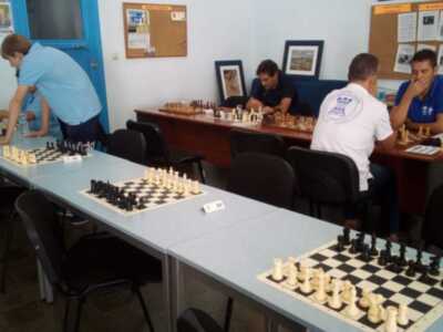 Jugadores de ajedrez en una sala de juego, con mesas y tableros de ajedrez organizados para un torneo.