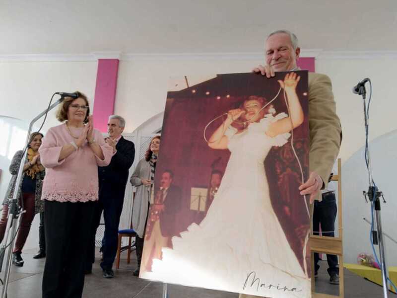 Celebración con retrato de artista cantante, aplausos y homenaje en el escenario.