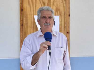 Hombre hablando en un micrófono, frente a una puerta de madera.