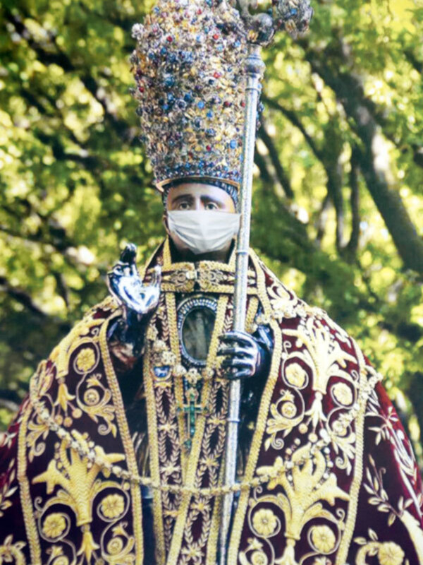 Imponente sacerdote con vestimentas ornamentales y casulla, sosteniendo un bastón ceremonial en un entorno natural.