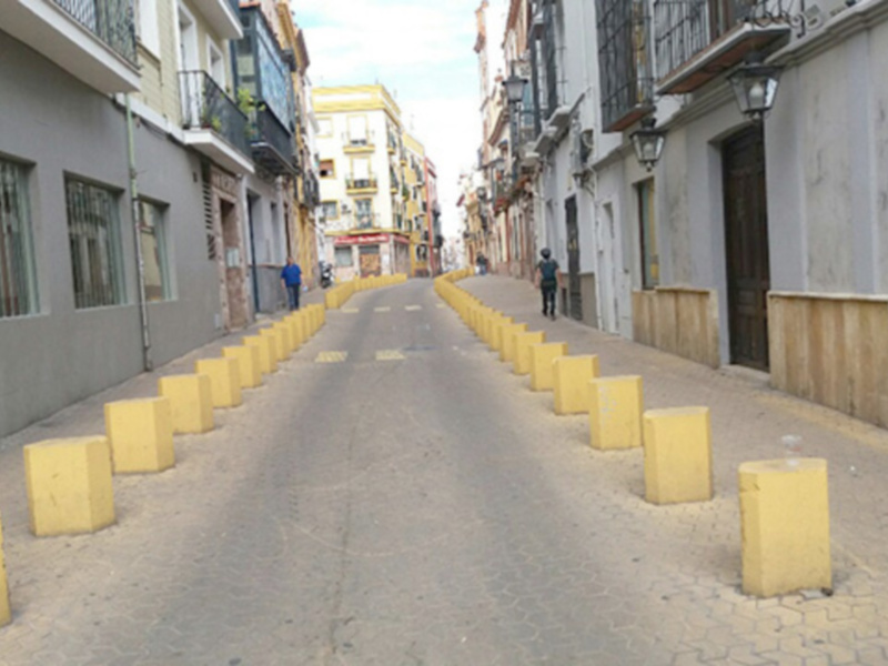 Ejemplo de pié de foto: "Calle desierta con bloques amarillos en el asfalto. Edificios de colores a ambos lados.天空晴朗。"