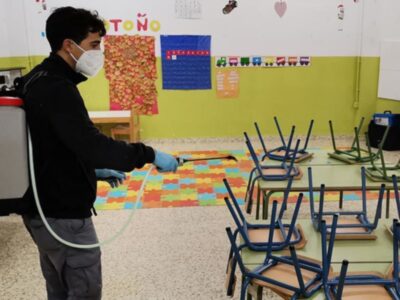 Un trabajador desinfecta una escuela, preparando los espacios para la vuelta a clases.