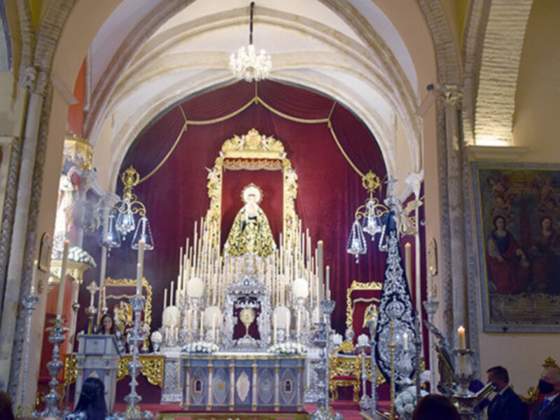 Interior de una iglesia con altares dorados, candelabros y estatuas religiosas.