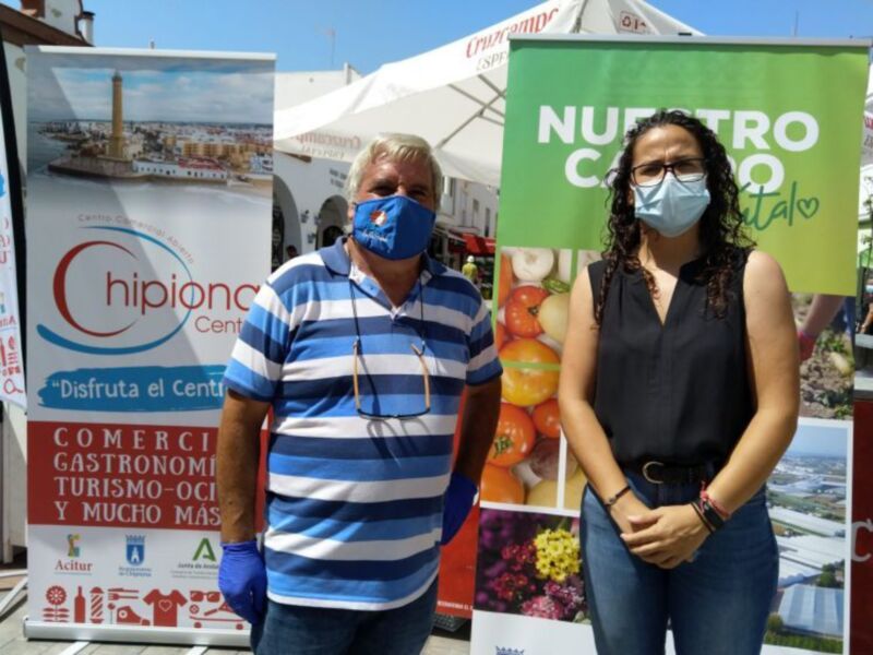 Personas con mascarillas y guantes en un evento promocional del 'Centro Comercial Chipiona' en Chipiona, España.