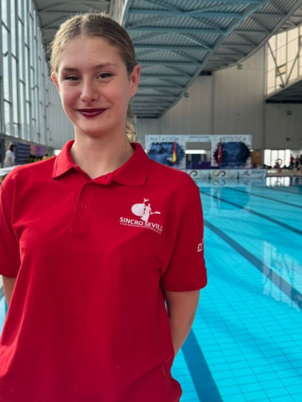 Estudiante de sincronización posando frente a una piscina en un centro deportivo.