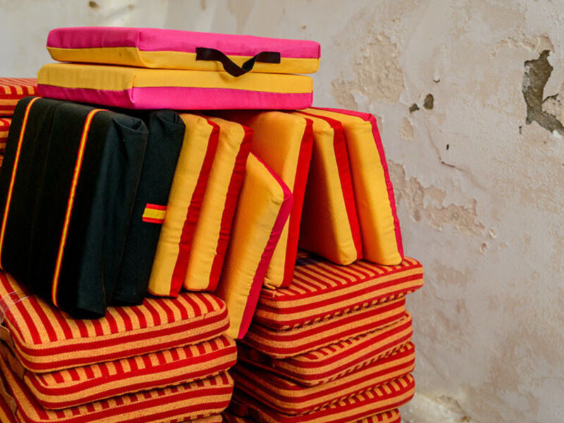 Pila de almohadones de colores en una pared con grietas.