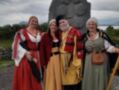 Personas vestidas con trajes medievales posan junto a un monumento en un entorno rural.