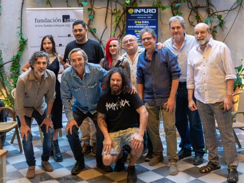 Grupos de personas posando frente a una bandera y un cartel con la palabra "INPURO". La imagen muestra una reunión o evento en un entorno interior, con plantas y sillas alrededor.