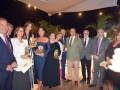 Una imagen de una gala o evento formal donde varias personas están posando con sus premios. La escena está iluminada con luces de techo y la gente está vestida formalmente, incluyendo trajes y vestidos. La atmósfera parece ser de celebración o reconocimiento.