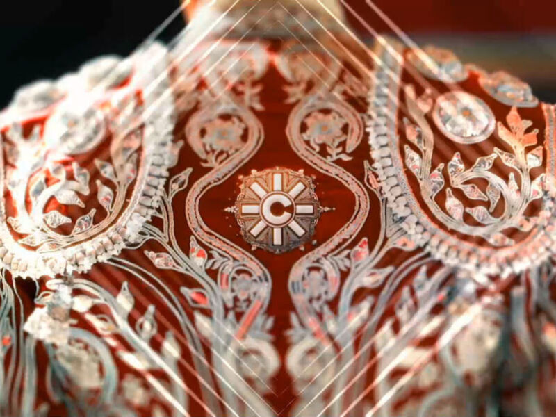 Imagen de una prenda de vestir con bordados en tonos rojos y blancos, destacando detalles ornamentales.